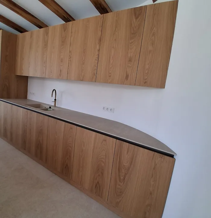 Dębowa kuchnia z ceramicznym blatem pod drewnianym stropem